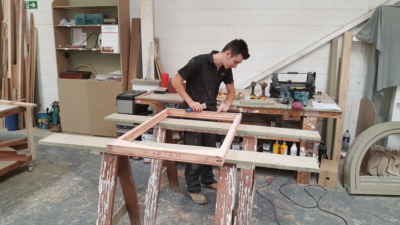 Young lad makes wooden window frames and is happy