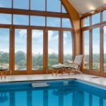 gallery pool with massive arched wooden windows and lift and slide patio doors