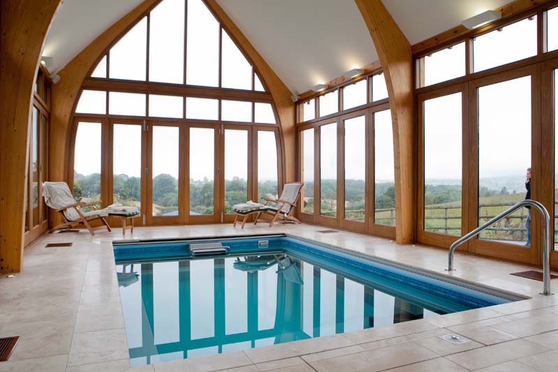 Tutbury sliding fold windows in Glulam structure swimming pool internal stained hardwood