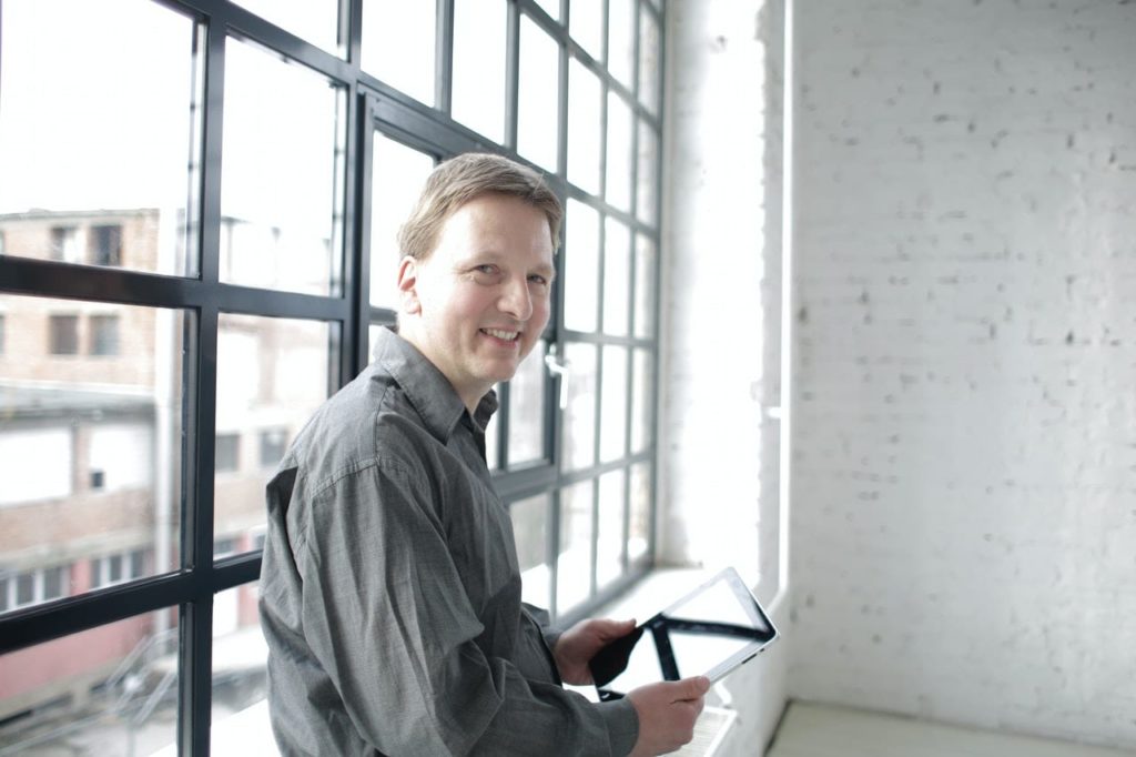 Who sells timber windows? A timber window reseller in front of a large window in loft style office where he has the option to buy timber windows