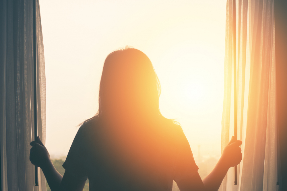 U values in double glazing - a silhouette of awoman at a window with strong sunlight shining throughj