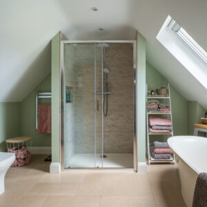A minimalist bathroom with a walk-in shower, freestanding bathtub, oak beams, bespoke red grandis timber skylight enhancing the natural light.
